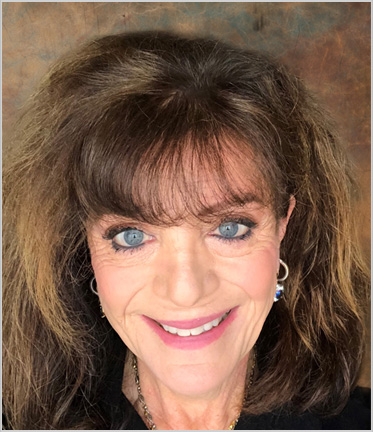 Smiling woman with brown hair and earrings.